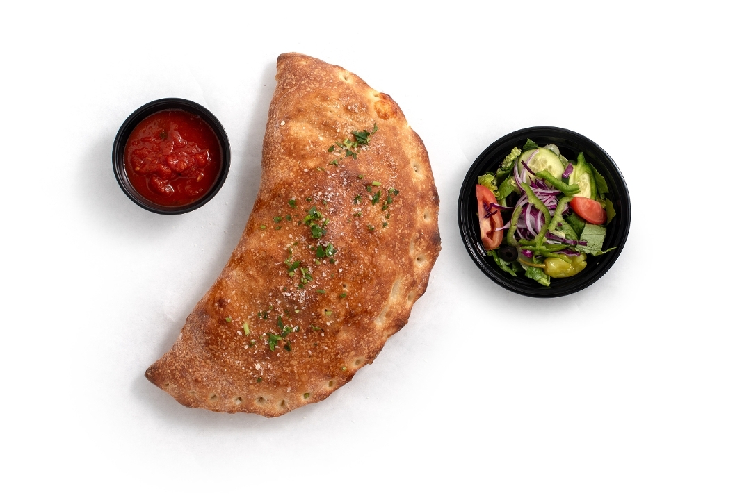Pepperoni calzone served with a side salad and marinara sauce